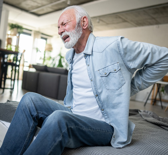 Senior-man-suffering-from-back-pain-while-sitting-on-bed