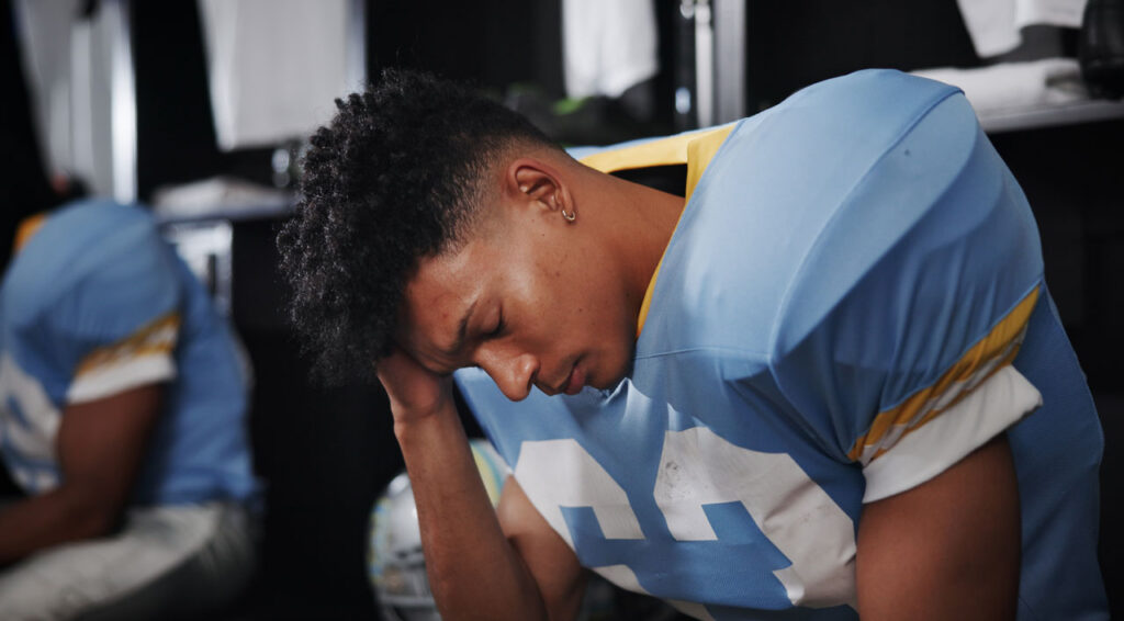 football-player-sitting-on-the-bench-with-his-head-down football-player-sitting-on-the-bench-with-his-head-down